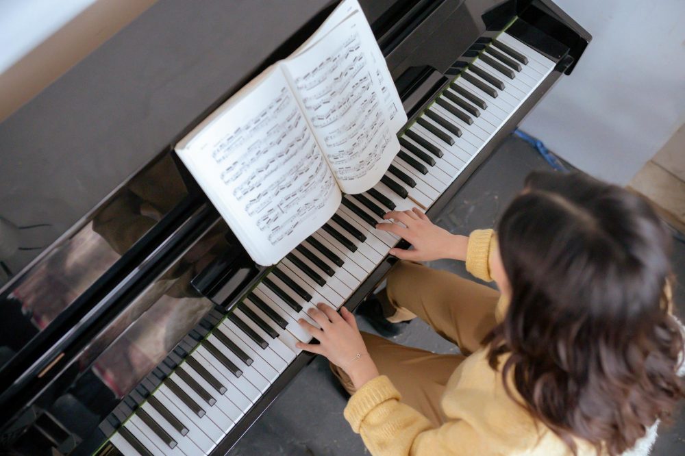 anonymous female playing piano near music book in room